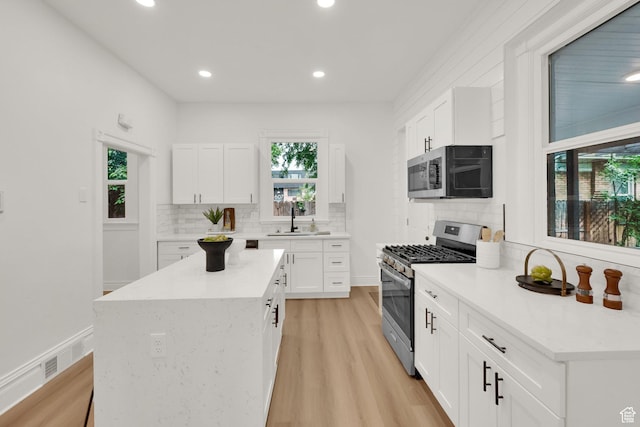532 E 600 S, Salt Lake City, UT 84102 - kitchen featuring stainless steel appliances, a sink, decorative backsplash, white cabinets, and light wood-style floors