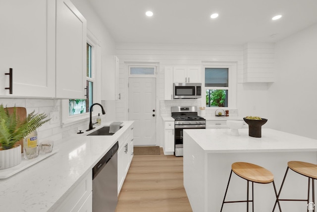 532 E 600 S, Salt Lake City, UT 84102 - kitchen featuring appliances with stainless steel finishes, a sink, a kitchen breakfast bar, decorative backsplash, and white cabinetry