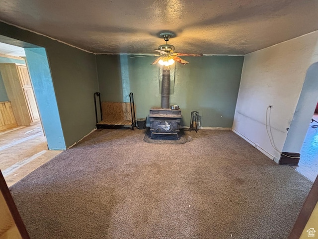 149 Thomas Fork Ln, Geneva, ID 83238 - carpeted empty room featuring a wood stove, ceiling fan, and a textured ceiling