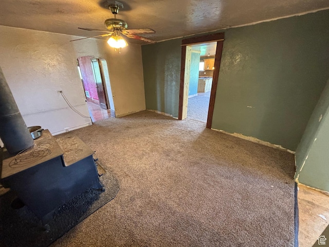 149 Thomas Fork Ln, Geneva, ID 83238 - carpeted empty room with a wood stove, ceiling fan, and a textured wall