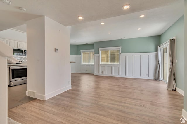 4917 W Stormy Meadow Dr, Riverton, UT 84096 - unfurnished living room featuring light wood-style floors, a decorative wall, a wainscoted wall, and recessed lighting