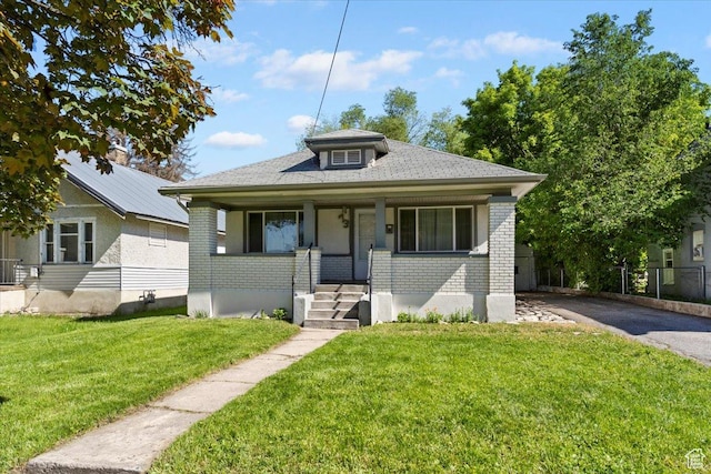 73 E 400 S, Logan, UT 84321 - bungalow-style house with brick siding, a front lawn, asphalt driveway, a porch, and central air condition unit