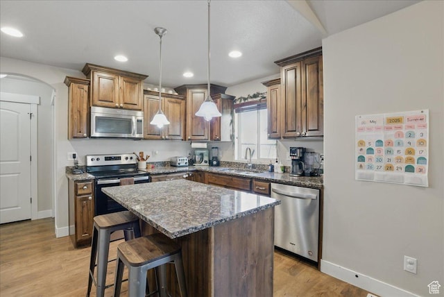 1467 S Lake View Ter, Saratoga Springs, UT 84045 - kitchen featuring appliances with stainless steel finishes, a sink, light wood-type flooring, arched walkways, and a breakfast bar area
