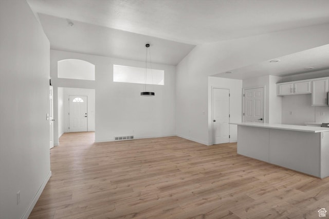 5094 W Pebblerock Cir S, West Jordan, UT 84081 - unfurnished living room with high vaulted ceiling, light wood-style flooring, and baseboards