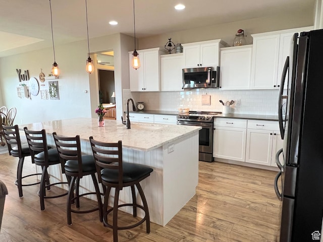 12137 N Montrose Dr, Highland, UT 84003 - kitchen featuring appliances with stainless steel finishes, a sink, decorative backsplash, light wood-style floors, and white cabinets