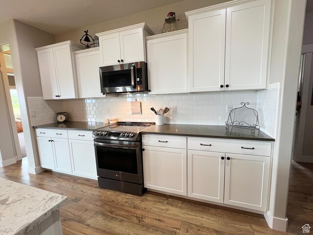 12137 N Montrose Dr, Highland, UT 84003 - kitchen with appliances with stainless steel finishes, light wood-style floors, white cabinets, decorative backsplash, and dark countertops