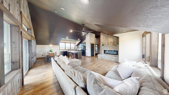 1164 S 1600 E, Preston, ID 83263 - living area with lofted ceiling, a stone fireplace, light wood-type flooring, ceiling fan, and baseboards
