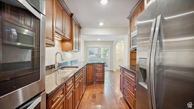 3263 Shadowbrook Cir N, Provo, UT 84604 - kitchen with appliances with stainless steel finishes, a sink, light wood-type flooring, dark stone countertops, and brown cabinetry