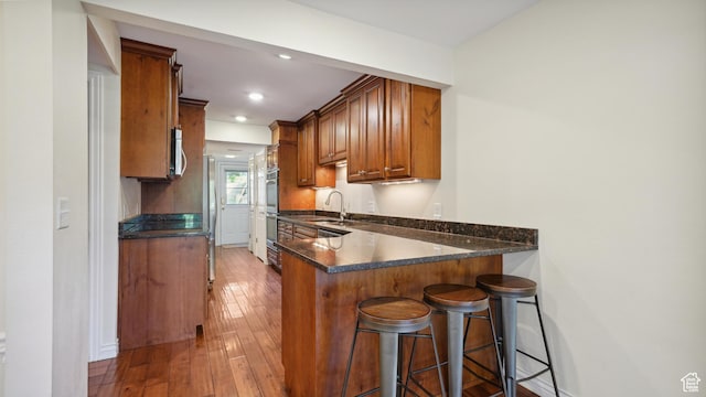 3263 Shadowbrook Cir N, Provo, UT 84604 - kitchen with stainless steel appliances, brown cabinetry, a breakfast bar, a sink, and a peninsula