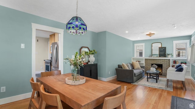 2504 S Dearborn St E, Salt Lake City, UT 84106 - dining space featuring baseboards, a textured ceiling, a fireplace, and light wood finished floors