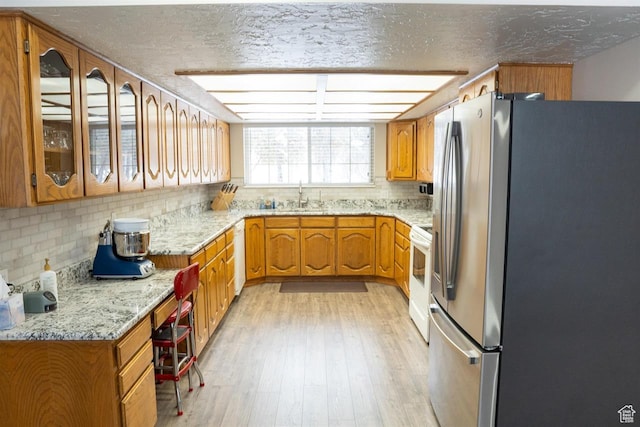 731 Pioneer Dr, Soda Springs, ID 83276 - kitchen with freestanding refrigerator, a sink, tasteful backsplash, brown cabinets, and light wood-style flooring