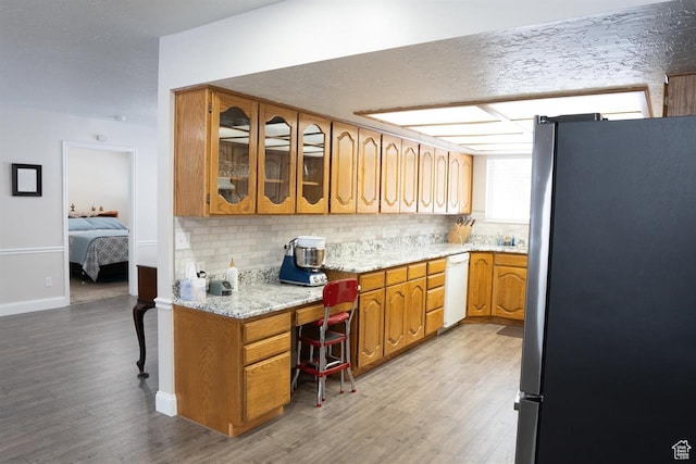 731 Pioneer Dr, Soda Springs, ID 83276 - kitchen with freestanding refrigerator, white dishwasher, light wood-style floors, backsplash, and brown cabinetry