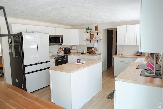 431 E Hooper Ave, Soda Springs, ID 83276 - kitchen featuring stainless steel appliances, light wood finished floors, white cabinets, a center island, and a textured ceiling