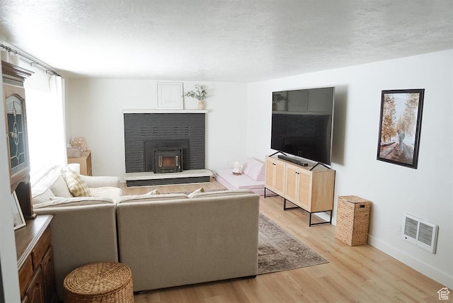 431 E Hooper Ave, Soda Springs, ID 83276 - living area featuring light wood-style floors, a brick fireplace, baseboards, and a textured ceiling