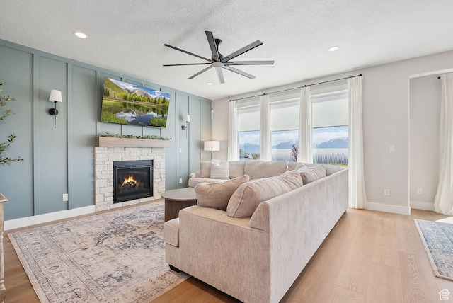13321 S Split Oak Dr, Herriman, UT 84096 - living room featuring ceiling fan, a stone fireplace, light wood-style floors, recessed lighting, and a textured ceiling