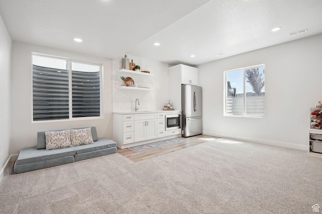 13321 S Split Oak Dr, Herriman, UT 84096 - living area featuring bar with sink, baseboards, recessed lighting, light colored carpet, and light wood-style floors