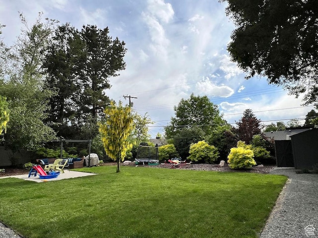 5466 S Woodcrest Dr, Holladay, UT 84117 - view of grassy yard with a trampoline and a patio area