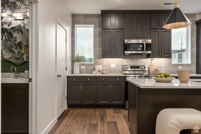 937 W Coalburn Way Unit 102, Murray, UT 84123 - kitchen featuring appliances with stainless steel finishes, a sink, wood finished floors, light countertops, and tasteful backsplash