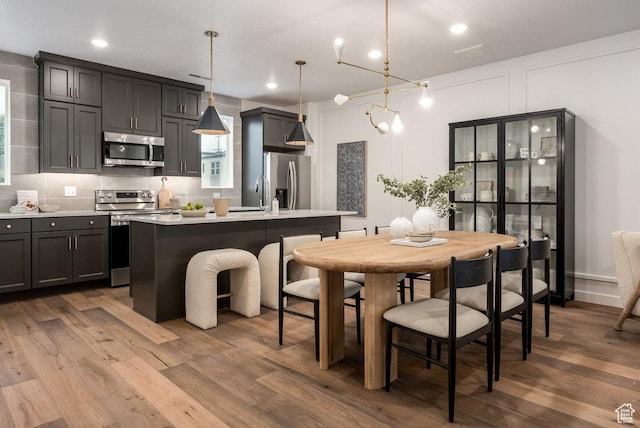 937 W Coalburn Way Unit 102, Murray, UT 84123 - kitchen featuring appliances with stainless steel finishes, light countertops, wood finished floors, a kitchen island with sink, and recessed lighting