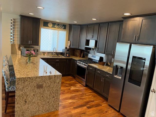 115 E 8469 S, Sandy, UT 84070 - kitchen featuring stainless steel appliances, a sink, a peninsula, wood finished floors, and light stone countertops