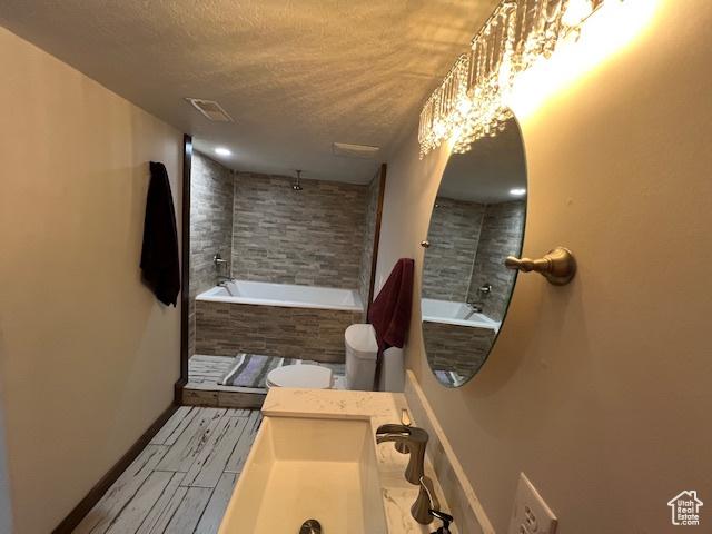 115 E 8469 S, Sandy, UT 84070 - bathroom with a textured ceiling, a relaxing tiled tub, toilet, baseboards, and a tile shower