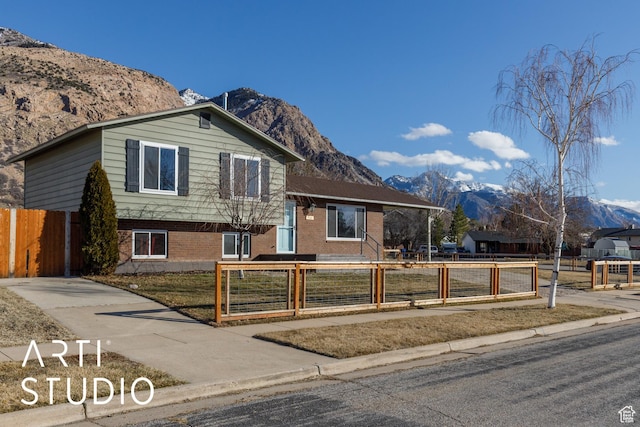 1280 N Gramercy Ave, Ogden, UT 84404 - split level home with a mountain view, a fenced front yard, and brick siding