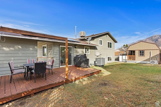1280 N Gramercy Ave, Ogden, UT 84404 - rear view of house featuring solar panels, outdoor dining space, a lawn, central AC unit, and a deck