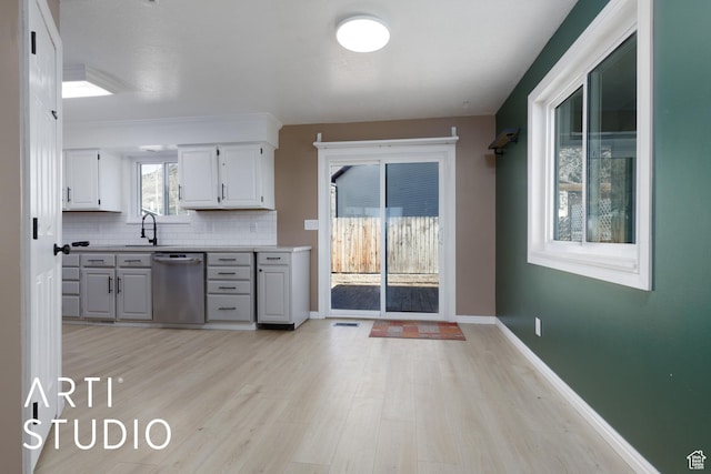 1280 N Gramercy Ave, Ogden, UT 84404 - kitchen featuring stainless steel dishwasher, light wood-type flooring, a sink, light countertops, and tasteful backsplash