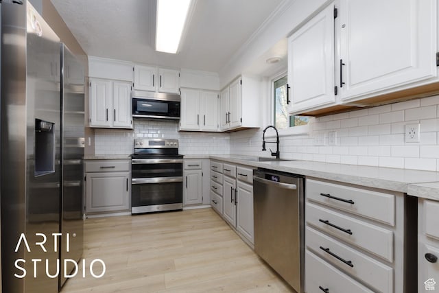 1280 N Gramercy Ave, Ogden, UT 84404 - kitchen with stainless steel appliances, a sink, gray cabinetry, light wood-style flooring, and decorative backsplash