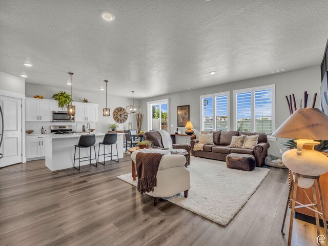 1136 W 1810 S, Orem, UT 84058 - living room featuring a textured ceiling, wood finished floors, recessed lighting, and a chandelier