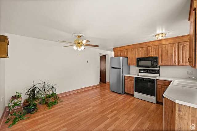 3279 W Crestfield, West Valley City, UT 84119 - kitchen featuring white electric stove, freestanding refrigerator, black microwave, a sink, and brown cabinetry