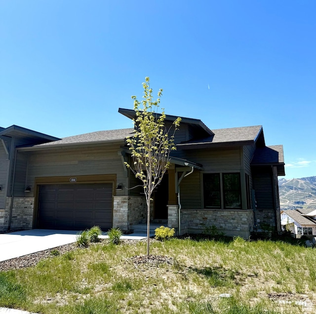11661 N Shoreline Dr, Hideout, UT 84036 - view of front of house with stone siding, a garage, concrete driveway, a mountain view, and roof with shingles