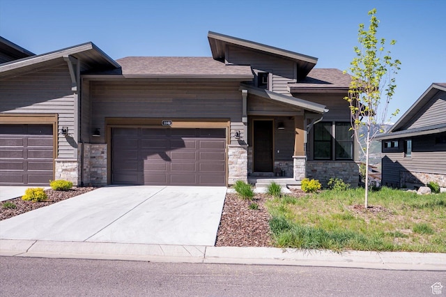 11661 N Shoreline Dr, Hideout, UT 84036 - view of front of house featuring an attached garage, concrete driveway, stone siding, and roof with shingles