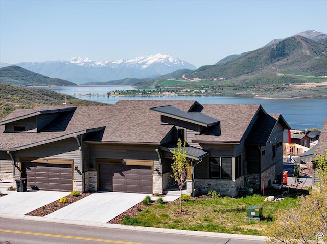 11661 N Shoreline Dr, Hideout, UT 84036 - view of front of home with stone siding, a water and mountain view, a garage, roof with shingles, and concrete driveway