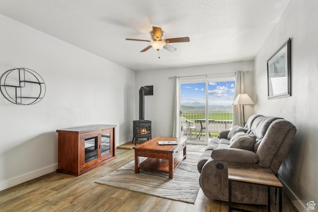 595 S Main St Unit 26, Kamas, UT 84036 - living room featuring a wood stove, ceiling fan, wood finished floors, and baseboards