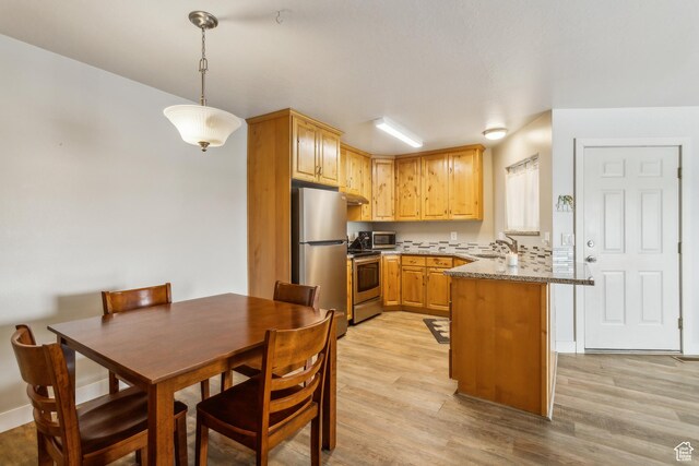595 S Main St Unit 26, Kamas, UT 84036 - kitchen with appliances with stainless steel finishes, a peninsula, light wood finished floors, and a sink