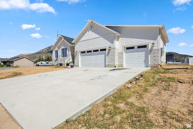 1228 N 100 E, Nephi, UT 84648 - view of front of house with board and batten siding, a garage, a mountain view, driveway, and stone siding