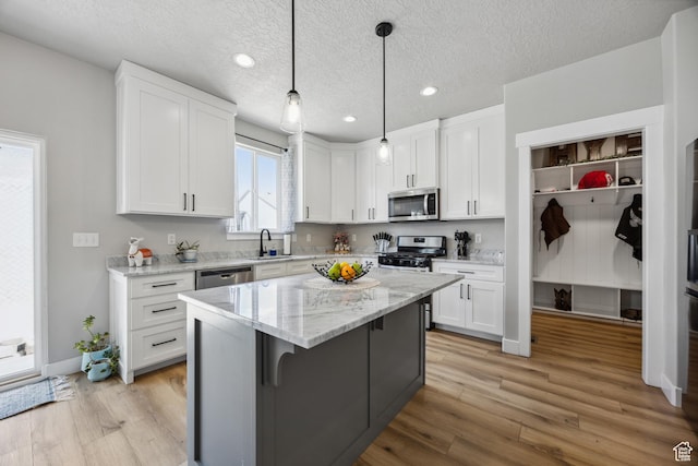 1228 N 100 E, Nephi, UT 84648 - kitchen featuring appliances with stainless steel finishes, a sink, white cabinets, light wood-type flooring, and a kitchen island