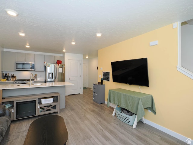 3906 S Bowie Dr W, Magna, UT 84044 - living area featuring light wood-style floors, baseboards, recessed lighting, and a textured ceiling