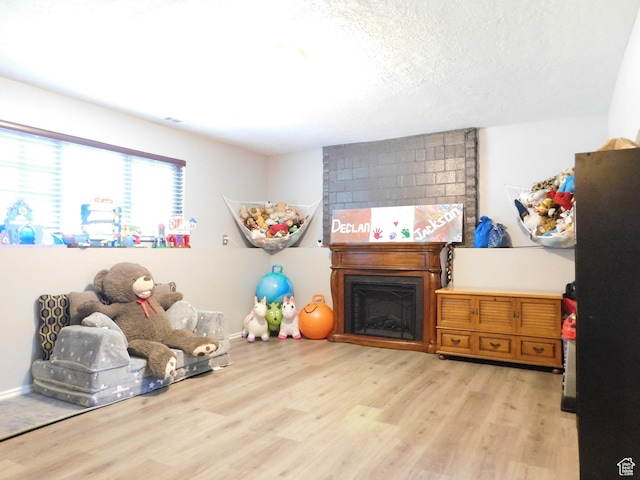 9467 S 250 E, Sandy, UT 84070 - playroom featuring light wood-style floors, a textured ceiling, and a fireplace
