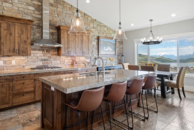 10371 N Sightline Cir, Hideout, UT 84036 - kitchen featuring wall chimney exhaust hood, a sink, stainless steel gas stovetop, an island with sink, and vaulted ceiling