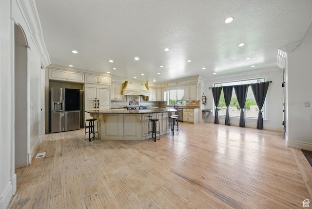 62 W 225 N, Lindon, UT 84042 - kitchen featuring stainless steel fridge, a kitchen breakfast bar, light wood-style flooring, baseboards, and cream cabinetry