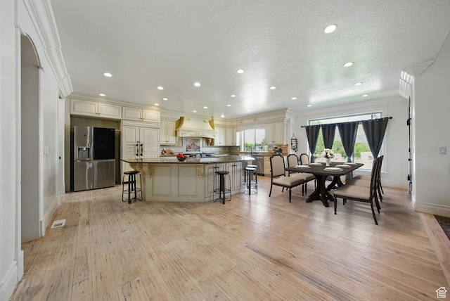 62 W 225 N, Lindon, UT 84042 - kitchen with stainless steel fridge, baseboards, a kitchen breakfast bar, light wood-style floors, and cream cabinets