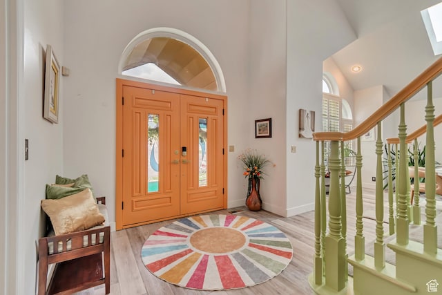 11198 S Wyngate Ln E, Sandy, UT 84092 - foyer featuring light wood-type flooring, high vaulted ceiling, a skylight, baseboards, and stairway