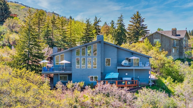 7340 Buckboard Dr N, Park City, UT 84098 - rear view of house with a chimney, a balcony, a deck, and a wooded view