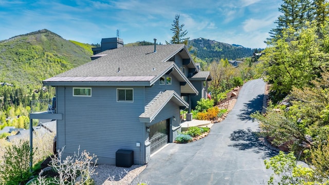 7340 Buckboard Dr N, Park City, UT 84098 - view of side of home featuring a mountain view, asphalt driveway, a chimney, and a shingled roof