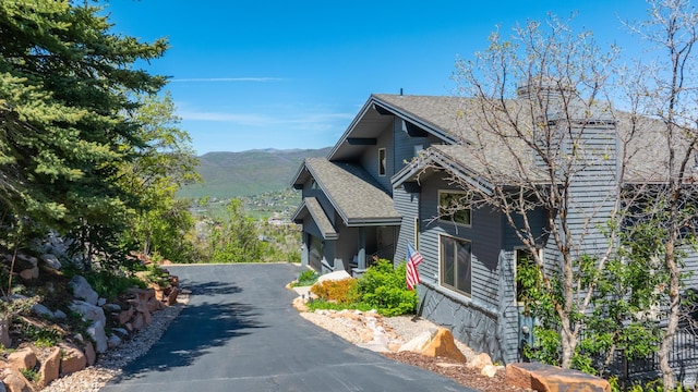 7340 Buckboard Dr N, Park City, UT 84098 - view of home's exterior featuring a mountain view, roof with shingles, a chimney, and asphalt driveway