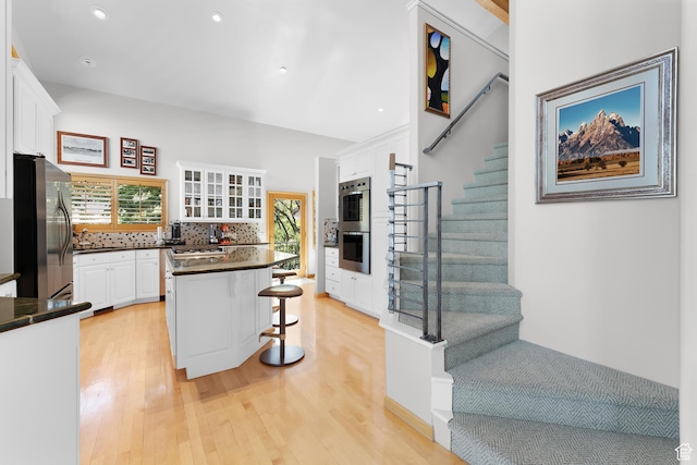 7340 Buckboard Dr N, Park City, UT 84098 - kitchen with stainless steel appliances, dark countertops, a breakfast bar, white cabinets, and light wood-style floors