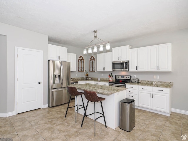 385 E 570 S, American Fork, UT 84003 - kitchen with appliances with stainless steel finishes, a breakfast bar area, white cabinetry, a kitchen island, and light stone countertops