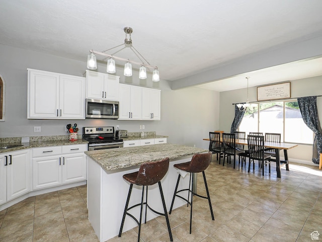 385 E 570 S, American Fork, UT 84003 - kitchen featuring stainless steel appliances, light stone countertops, a center island, and white cabinetry